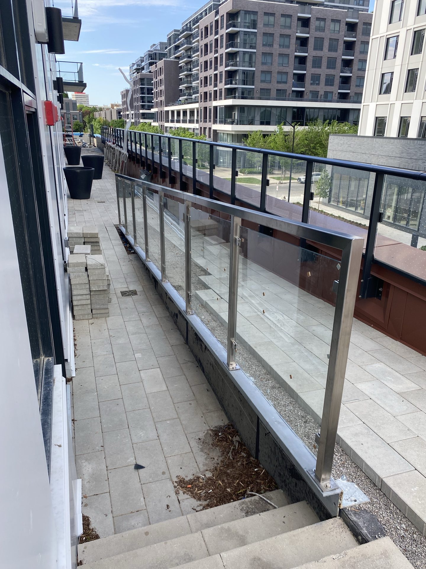 Stainless steel and glass railing along a rooftop terrace overlooking the city